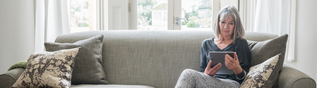 A mature woman using a tablet in her living room