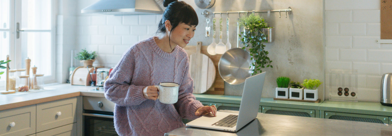 a woman in her kitchen on her laptop computer