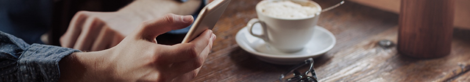 a person at a coffee shop viewing their mobile phone
